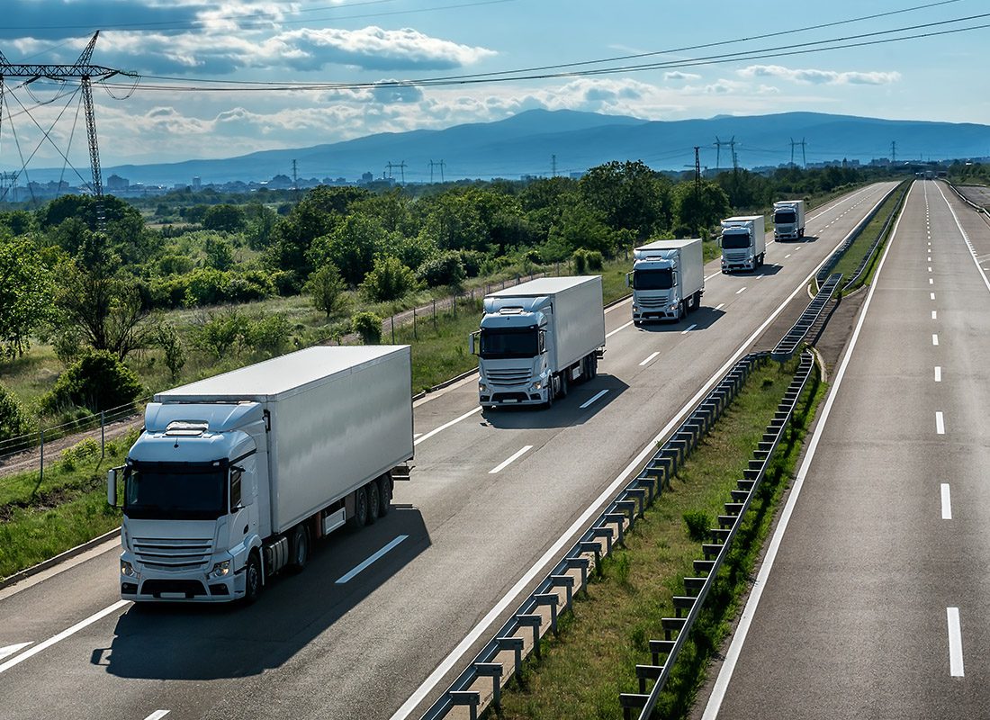 Insurance by Industry - Fleet of Trucks Drive Down a Open Road on a Sunny Day
