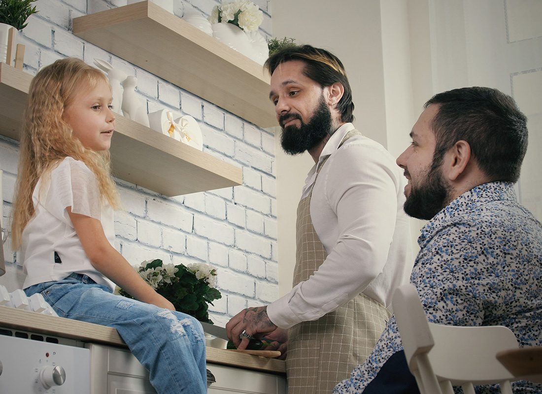Personal Insurance - Two Fathers Look at Their Daughter and Smile in the Kitchen at Home