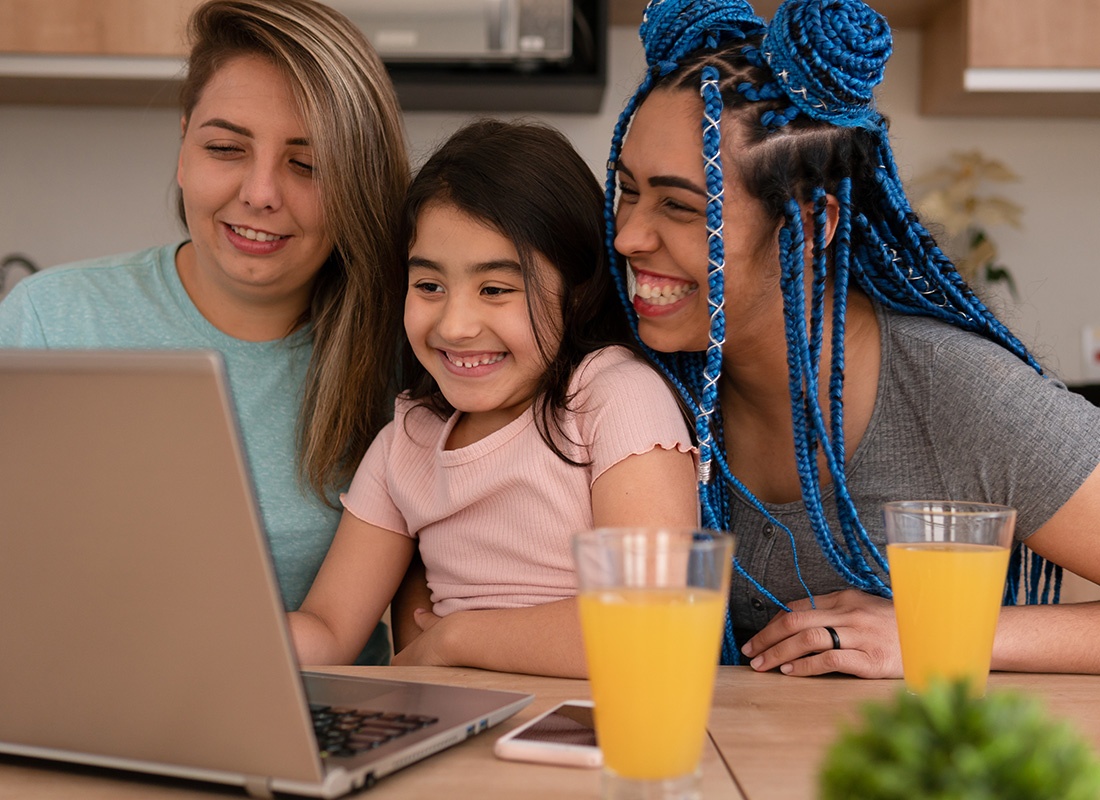 Service Center - Two Mothers and Their Daughter Smile as They Use a Laptop at Home